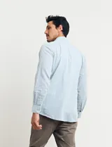 Camisa celeste de manga larga con cuello button-down, confeccionada en tejido rústico de algodón y lino.