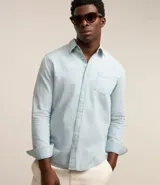 Camisa de jean celeste para hombre, de manga larga, con cuello solapa, abotonado delantero y bolsillo en el pecho.