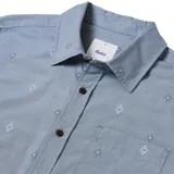 Camisa celeste con estampado de flores blancas, de manga corta y corte clásico.