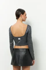 Top corto de fiesta color negro con brillos, de mangas largas y cuello redondo.