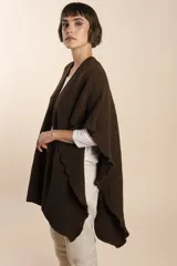 Ruana color crema tejida en punto fantasía con efecto de volado en los bordes.