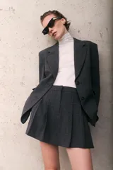 Short pollera gris oscuro con estampado a cuadros (Príncipe de Gales o similar), de corte acampanado con pliegues en el frente.