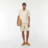 Camisa de manga corta color crema con textura de punto y botones de madera.