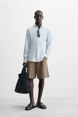 Camisa celeste de lino, de corte recto, manga larga y cuello clásico.