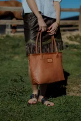 Bolso tipo tote de cuero color marrón con diseño tejido. Tiene bolsillo interno, porta llaves y cierre.