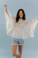 Camisa azul de algodón con cuello alto y mangas largas acampanadas con detalles de puntilla.