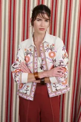 Chaqueta color crudo con bordados de flores azules y naranjas.