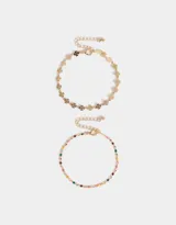 Set de dos pulseras doradas con dijes: una con dijes de trébol y otra con dijes esmaltados de colores.