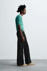 Pantalón negro de corte recto con bordados florales a tono, bolsillos laterales y traseros de vivo. Cierre frontal con cremallera y botón.