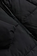 Campera puffer larga negra con capucha, cuello elevado, cierre frontal, bolsillos insertados y elástico oculto en los puños.