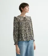 Remera de viscosa con cuello redondo, abertura con amarre, manga larga con volantes en hombros y puños, y estampado de flores.