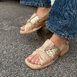 Sandalias bajas color dorado con tiras cruzadas y detalle de textura tipo piel de cocodrilo.