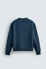 Sudadera azul petróleo de corte relajado, cuello redondo, manga larga, bolsillo tipo canguro y terminaciones en rib.