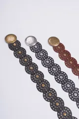 Cinturón de cuero con diseño de discos circulares superpuestos, adornados con tachas y hebillas redondas grabadas. Disponible en negro, marrón y con hebillas en tonos dorado y plateado.