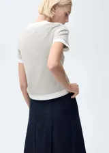 Camiseta color gris claro con cuello en V y mangas cortas. Diseño de doble capa con remera blanca debajo.