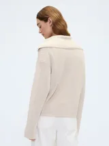 Sweater color beige de tejido de punto con cuello polo y cierre de medio cierre.