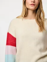 Sweater de punto color crema con cuello redondo y mangas largas con rayas horizontales en colores rojo, celeste, azul y rosa.