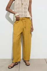Pantalón color verde oliva de tiro alto, corte ancho y largo 7/8. Tiene cintura elástica ajustable con cordón, bolsillos de plastrón en delantero y espalda.