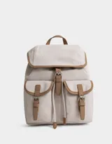 Mochila color crema con detalles en marrón, con solapa superior con cierre de hebilla, dos bolsillos frontales con cierre de hebilla, asa superior y correas ajustables para los hombros.