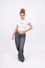 Remera blanca ajustada de jersey con lycra, con mangas cortas y estampado frontal con la frase "Break with the limits of reality" en letras cursivas negras.