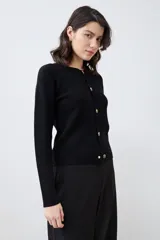 Chaqueta tejida negra con botones dorados, de corte clásico y mangas largas.