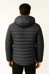 Campera acolchada negra con capucha, cierre frontal y bolsillos laterales. Presenta un diseño de costuras horizontales que crean un efecto puffer.