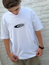 Remera blanca de corte oversize con un pequeño logo estampado en el pecho que dice "OSTEN" dentro de una forma ovalada negra.