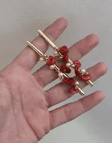 Par de caravanas con base dorada y piedras rojas y perlas.