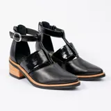 Zapato de cuero negro con detalle de charol, taco de madera con folia en cuero de 5cm, cierre YKK en talón, hebilla y elástico en el empeine.