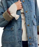 Campera de denim azul de corte holgado, con cuello de pana color verde militar y puños de pana acanalada del mismo color. Presenta cierre frontal con botones, cuatro bolsillos delanteros con solapa y botón, y dos bolsillos laterales.