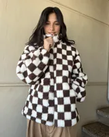 Campera de corderito a cuadros marrones y blancos, con cierre frontal y bolsillos laterales.