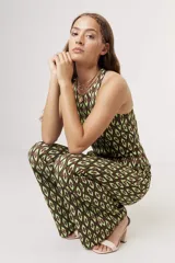 Top corto tipo crop top, sin mangas y con cuello halter. Presenta un estampado grande de flores en tonos verde claro, verde azulado y beige/crema.