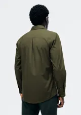 Camisa de vestir azul marino, de corte clásico, con cuello abotonado, manga larga y bolsillo en el pecho.