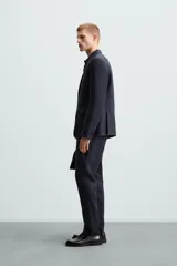 Pantalón de vestir azul marino, de corte recto, confeccionado en lino. Tiene bolsillos laterales y traseros con botón.