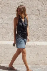 Top blanco de tejido satinado con cuello halter drapeado ajustable con lazada en el cuello y espalda descubierta con lazada.