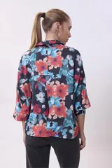 Camisa de mangas 3/4 con estampado floral en tonos naranja, celeste y verde sobre fondo negro.
