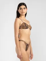 Conjunto de bikini de dos piezas con estampado de flores y caritas sonrientes en tonos rosados y naranjas. El corpiño es triangular con breteles finos y la bombacha es de tiro alto con cobertura mínima.