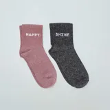 Pack de dos pares de medias cortas con brillos: un par rosa con la palabra 'Happy' y un par negro con la palabra 'Shine'.