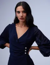 Vestido negro con escote en V y mangas abullonadas, detalle de botones en la cintura.