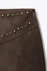 Pantalón marrón acampanado de tiro alto confeccionado en tejido efecto ante con detalle de tachas en la cintura.