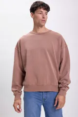 Buzo deportivo color visón, de corte holgado y cuello redondo.