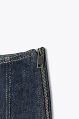 Falda midi de tiro alto confeccionada en denim azul oscuro. Presenta costuras a contraste y cierre lateral con cremallera metálica.