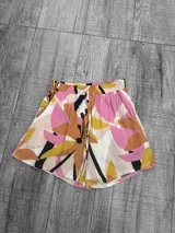 Short de fibra con estampado floral en tonos rosas, amarillos y negros, diseño suelto.