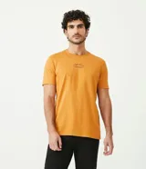 Remera color mostaza de corte slim fit, cuello redondo y manga corta. Presenta un estampado tipográfico en el pecho.