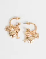 Aros dorados tipo argolla con dije de corazón y llave colgando.