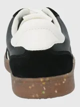 Zapatillas deportivas urbanas de mujer, color negro, con cordones blancos, suela marrón con motas de colores y detalles en blanco en el lateral.