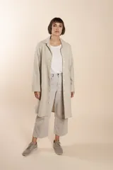 Camisa larga color crema con rayas verticales finas en gris, con botones dorados y bolsillo plaque en la delantera.