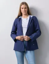 Campera impermeable azul con cierre central, bolsillos delanteros y lazo de ajuste en la cintura. Tiene avíos metálicos plateados y cierre oculto en la espalda para autoguardado.