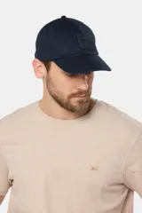 Gorro con visera azul marino, confeccionado en lona de algodón. Presenta un parche con logo de la marca en el frente.