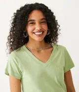 Blusa blanca de algodón con cuello en V, manga corta y bolsillo frontal.